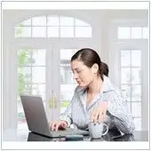 Remote Workers Unproductive? Fix It 3 woman working at a sunlit modern desk, balancing productivity and comfort with natural elements.