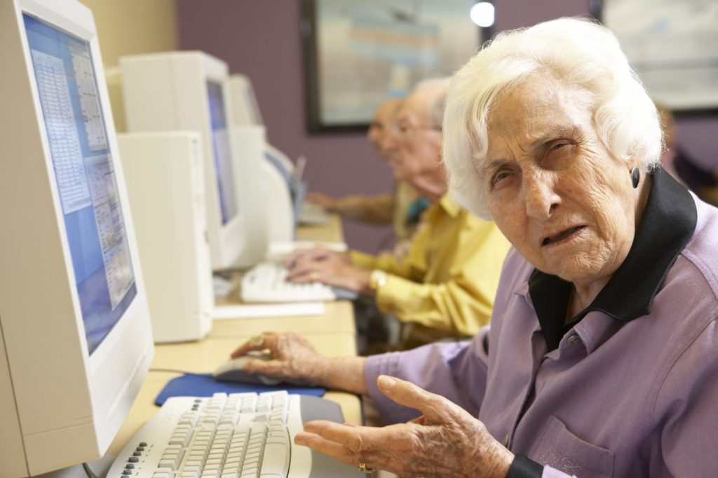 elderly individuals engaging in technology classes, showcasing curiosity and collaboration in a computer lab.