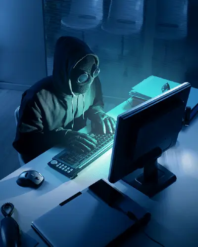 3 Ways That Hackers Steal Data From Small And Medium Businesses 3 hacker in a hoodie engaging in stealthy data theft activities in a dark environment.