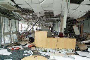 severely damaged office space with a collapsed ceiling and debris, reflecting chaos and neglect.