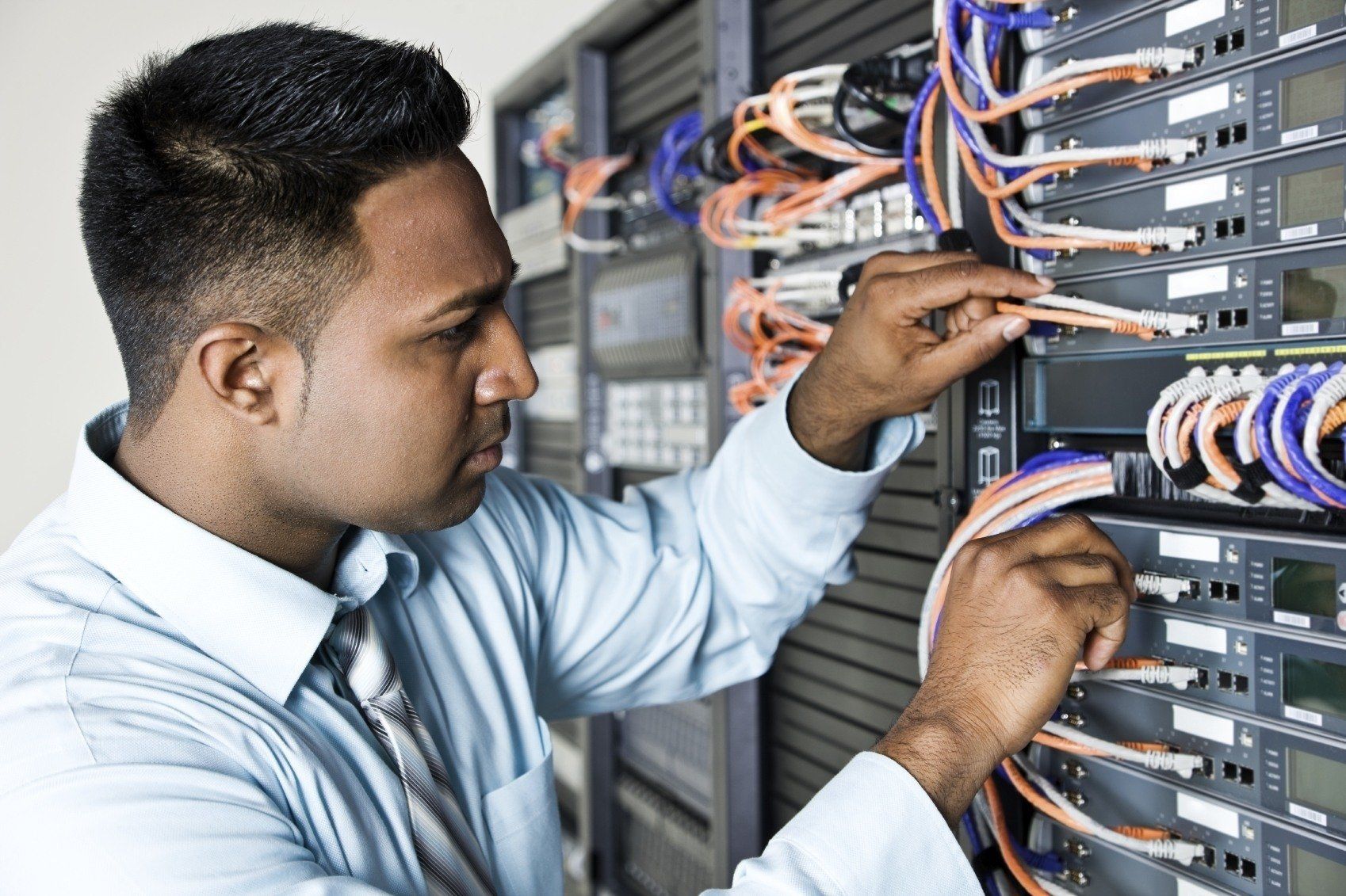 network technician skillfully managing colorful cables and equipment in a server rack.