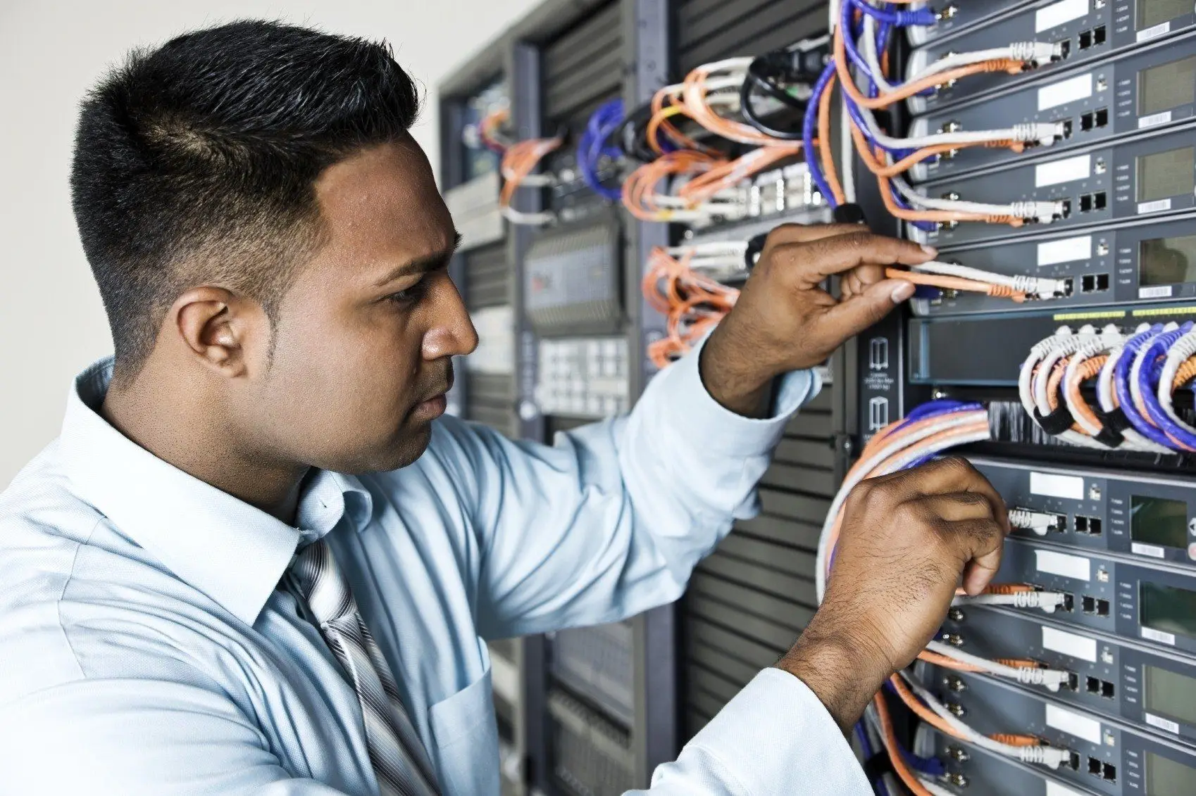 Network Technicians Expected On More Budgets 5 network technician skillfully managing colorful cables and equipment in a server rack.