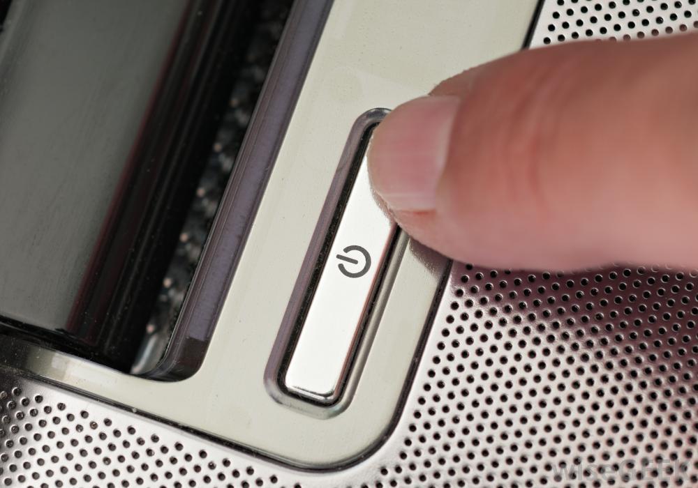 finger hovering over a sleek power button, symbolizing human interaction with modern technology.