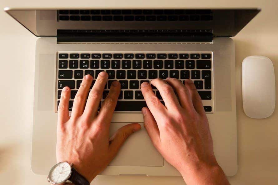 person typing on a laptop with a mouse, illustrating productivity and effective it support.