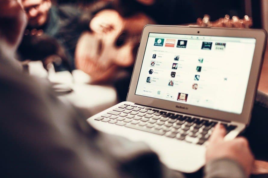 individual connects online in a café, browsing social media on a macbook air.