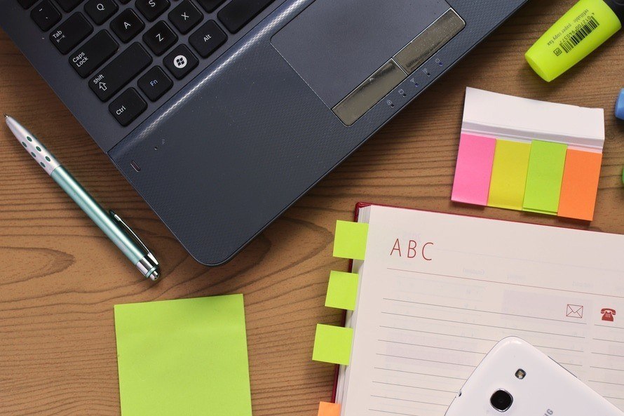 organized workspace featuring a laptop, notebook, colorful notes, and smartphone for enhanced productivity.