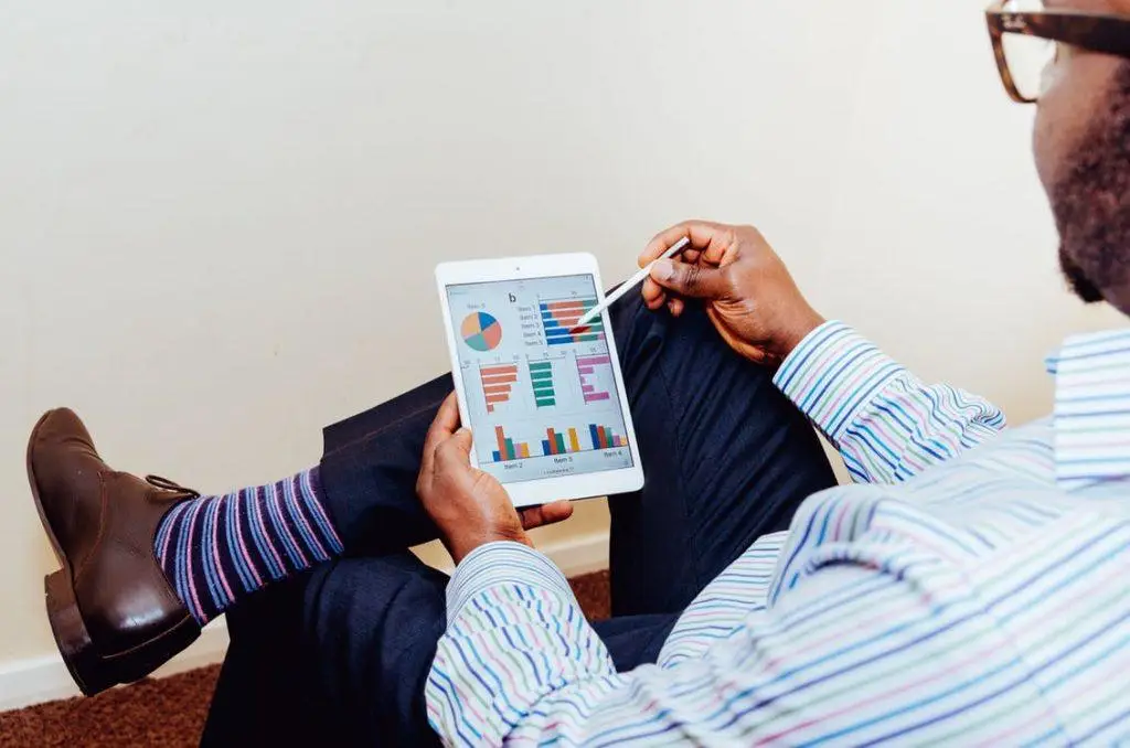 Backing Up Your Data: Analytics Help Manage Data Backup 5 professional man analyzes data on a tablet, blending style and focus in a modern office.