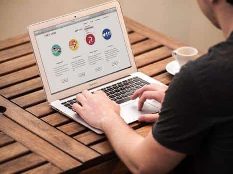 person using a macbook outdoors, enjoying coffee while exploring website security maintenance tips.