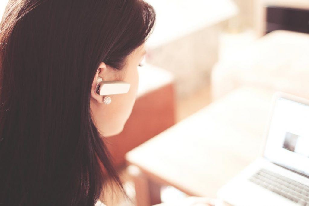 woman in headset focusing on laptop in a modern, cozy workspace.