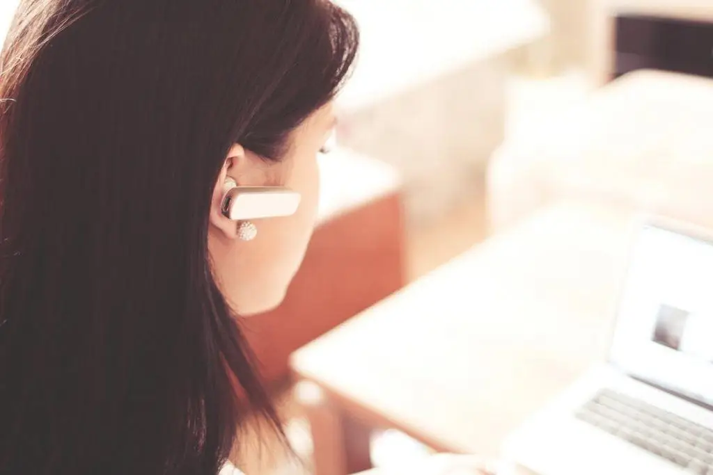Outsourcing It Service Management: Business Tips 1 woman in headset focusing on laptop in a modern, cozy workspace.