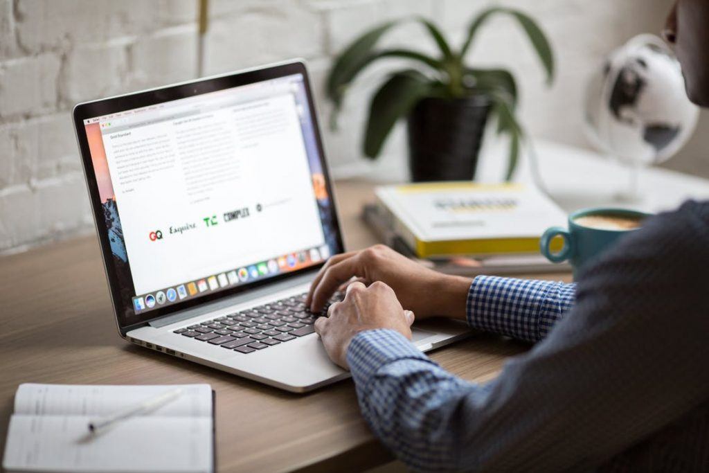 modern workspace with a macbook, coffee, notepad, and greenery for productivity and comfort.