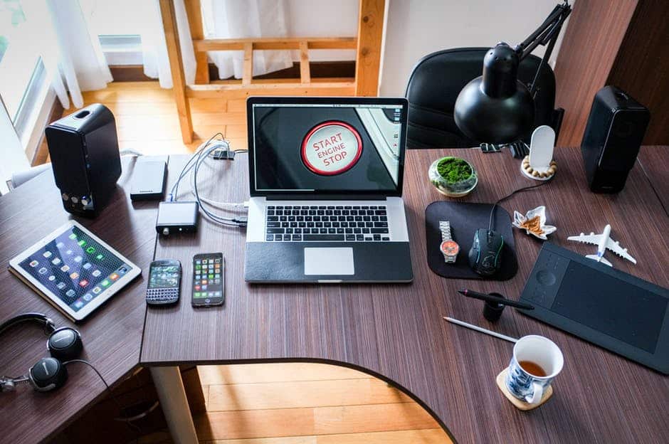 modern desk workspace featuring a laptop, speakers, graphics tablet, and coffee for productivity.