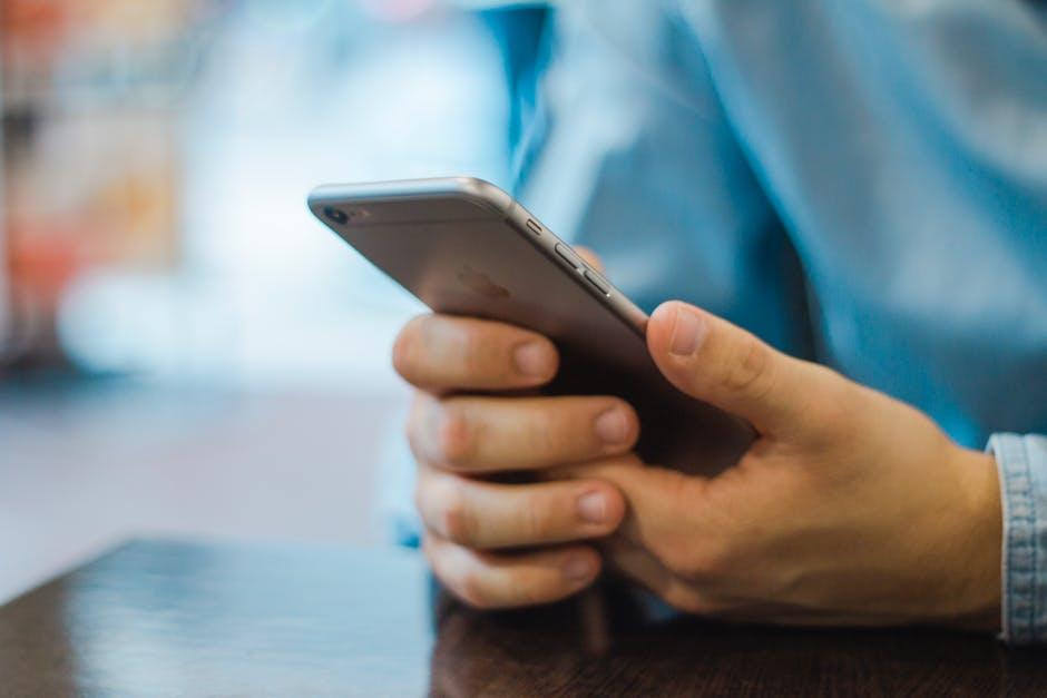 person comfortably using a smartphone, highlighting casual technology engagement in a café setting.