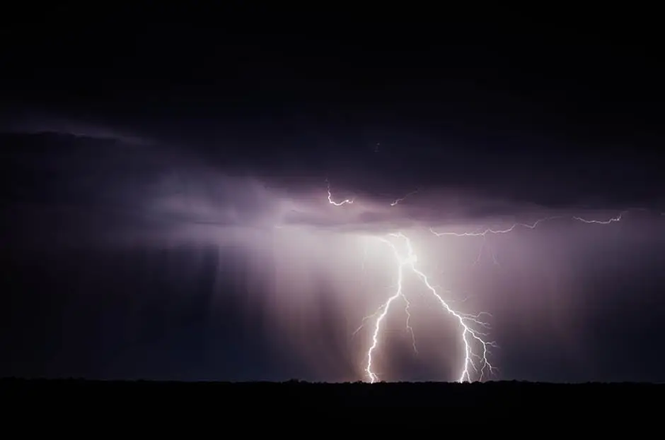 The Only 4 Disaster Recovery Tips You Need For Hurricane Season 1 dramatic lightning strike illuminates dark clouds above a shadowy field during a nighttime storm.