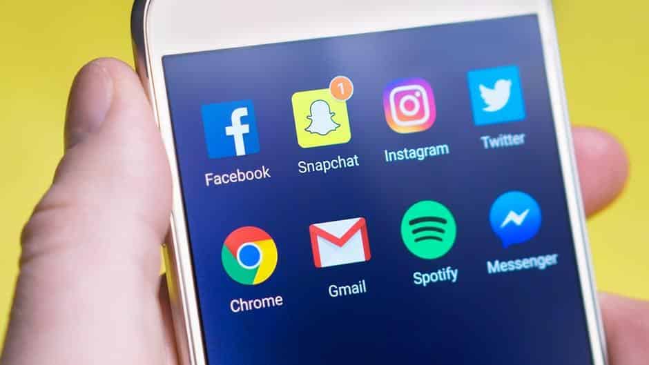 person interacting with smartphone displaying popular social media and utility app icons.