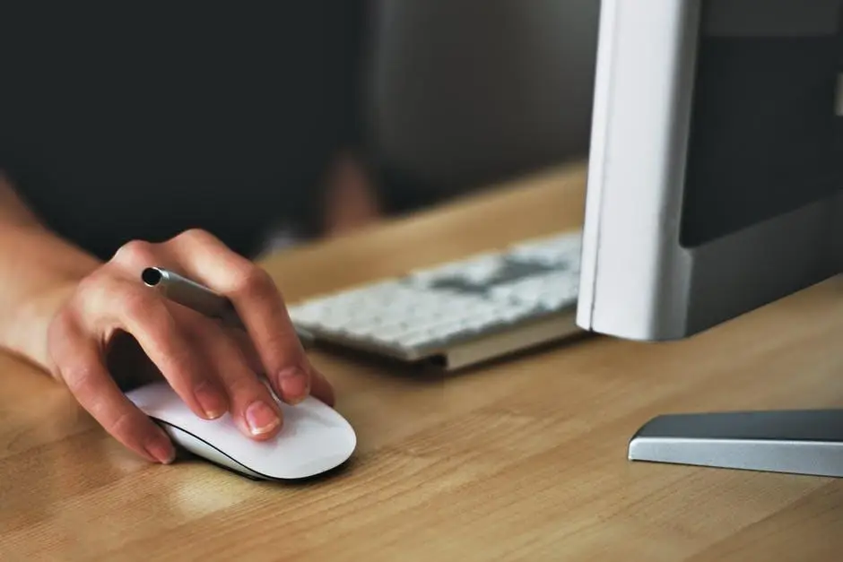 Computer Tip Of The Day: How Secure Are Your Passwords? 6 a hand poised on a white mouse in a modern, productive workspace.