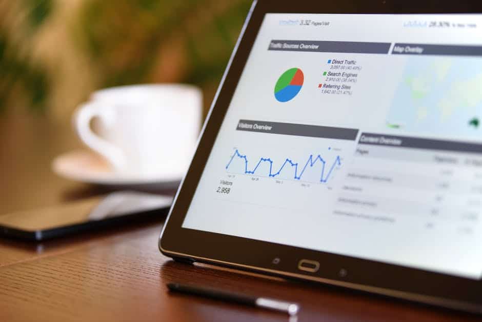 modern tablet displaying data insights on a wooden table with coffee cup and smartphone nearby.