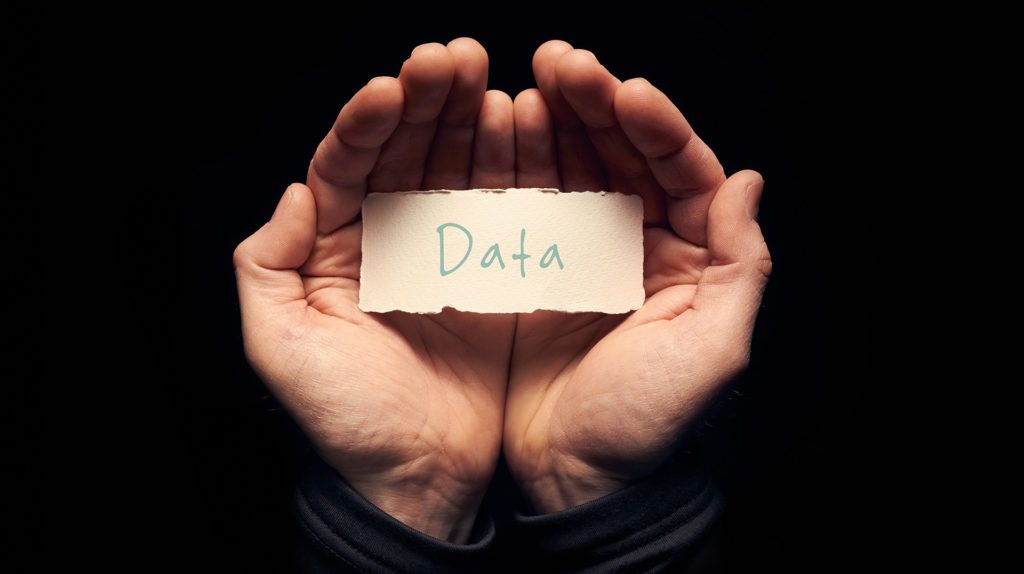 gentle hands cradling torn paper with data emphasize the importance of nurturing information.