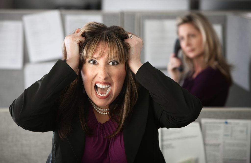 frustrated woman in office contrasts with calm colleague, highlighting workplace stress dynamics.