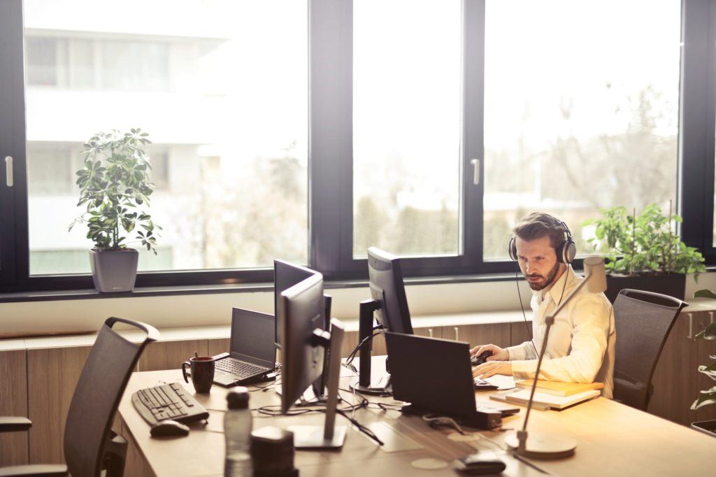 young man engaged in work at a modern desk in a bright, tech-enhanced office space.