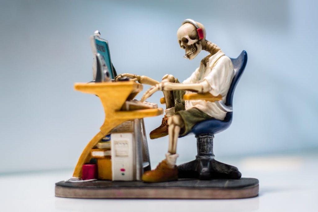 whimsical skeleton working at a colorful desk with a retro computer, blending humor and nostalgia.