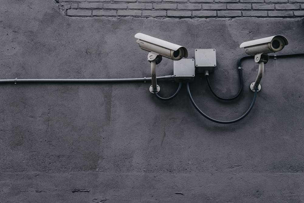 surveillance cameras on a gray wall, representing urban security and constant monitoring.