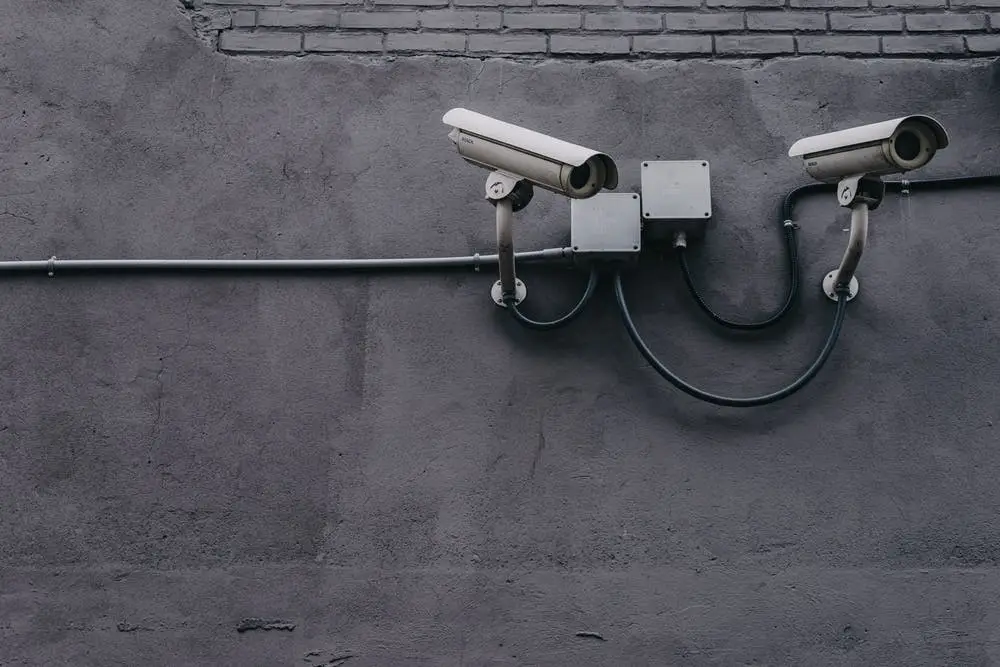 surveillance cameras on a gray wall, representing urban security and constant monitoring.