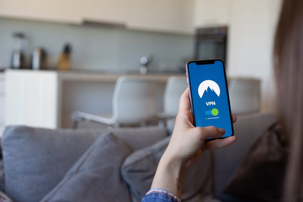 woman using a smartphone with a vpn app in a cozy, modern kitchen.