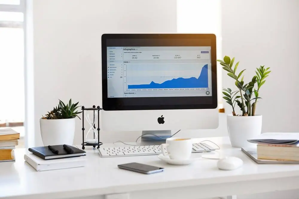 How To Leverage Technology For Your Business Growth 4 modern workspace with imac, plants, and books, fostering productivity and business growth.