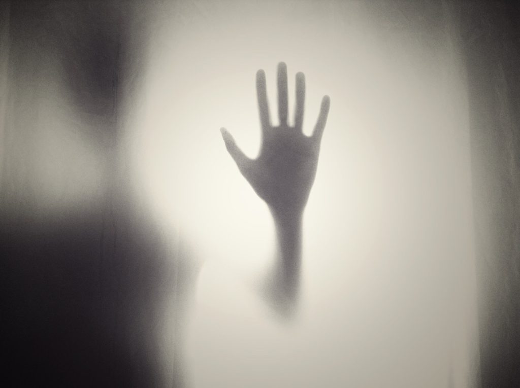 silhouette of a hand pressed against a foggy surface, conveying longing and connection.