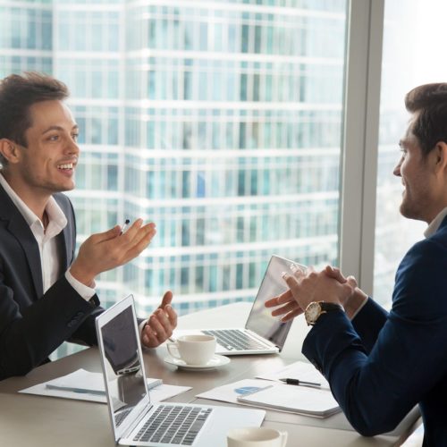 two professionals engage in a dynamic discussion in a modern office with city views.