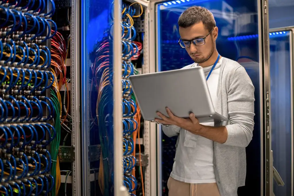 3 Critical Services Your Current It Support Is Missing 5 young it professional managing network infrastructure in a vibrant data center with colorful cables.