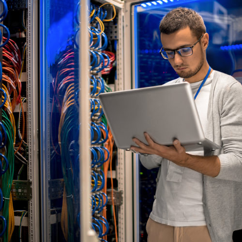 young it professional managing network infrastructure in a vibrant data center with colorful cables.