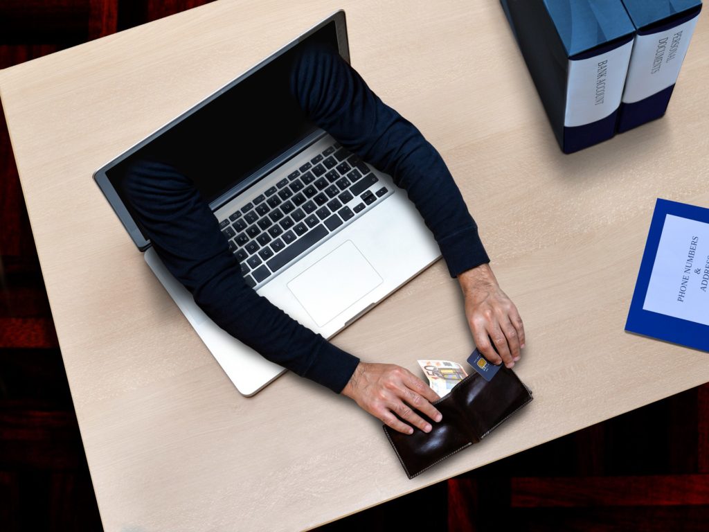surreal laptop portal with arms interacting with a wallet, symbolizing tech and finance integration.