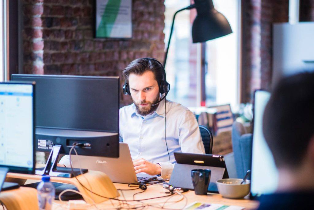 young professional focused on work at a modern office desk with multiple screens.