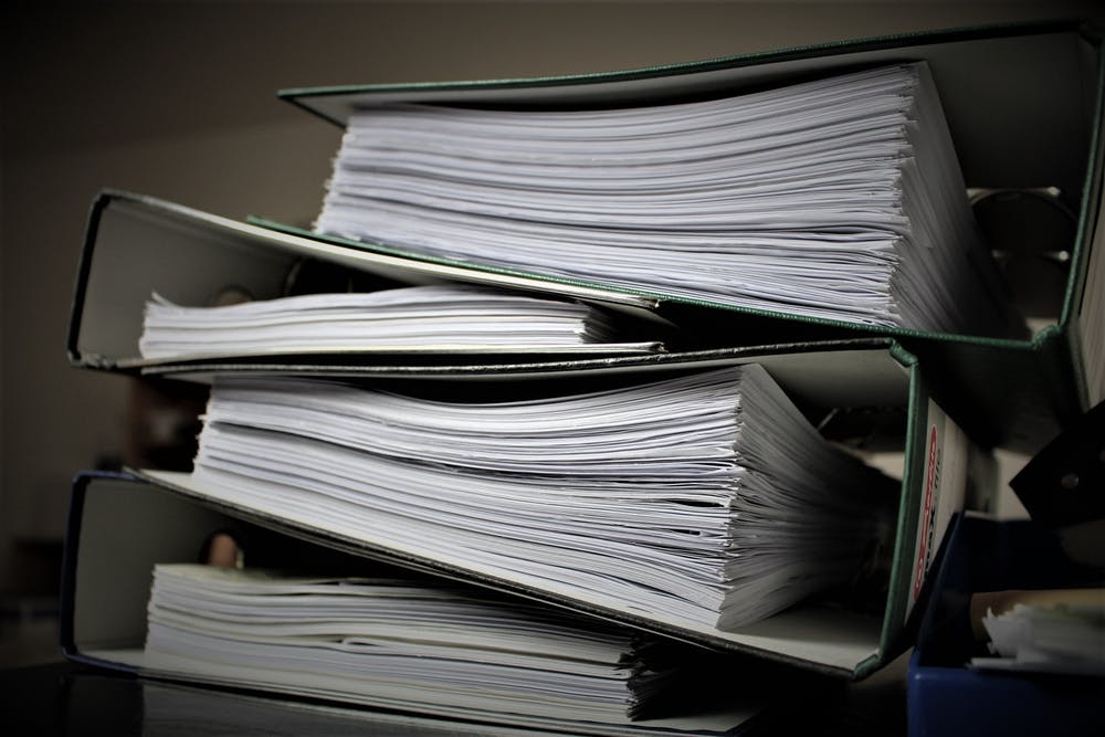 stack of green binders documenting organized information security policies for pandemic management.