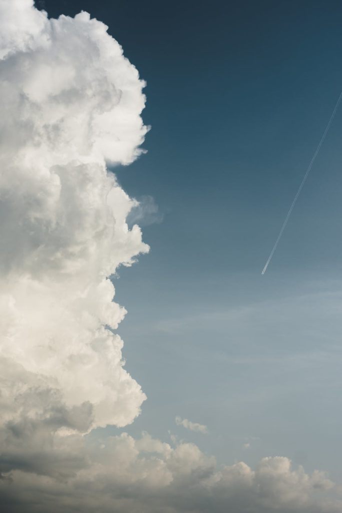 vast sky with billowy clouds and a jet contrail, creating a serene atmosphere.