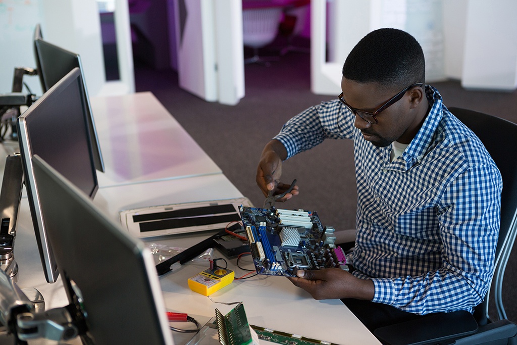technician focuses on computer motherboard amidst tools in a modern, organized tech workspace.