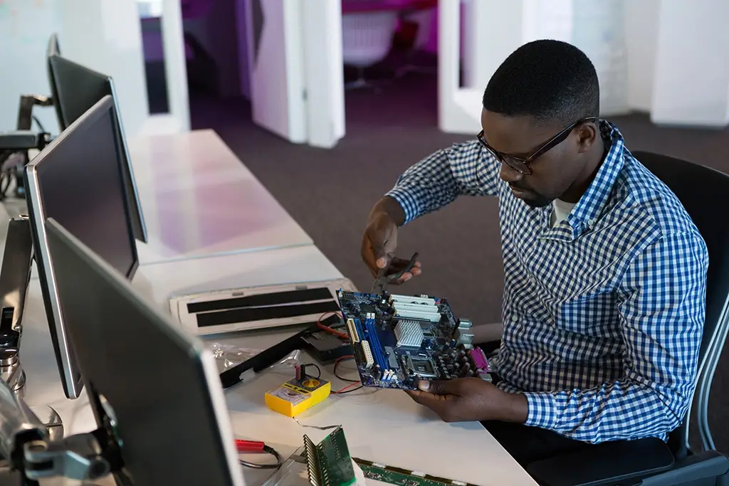 technician focuses on computer motherboard amidst tools in a modern, organized tech workspace.