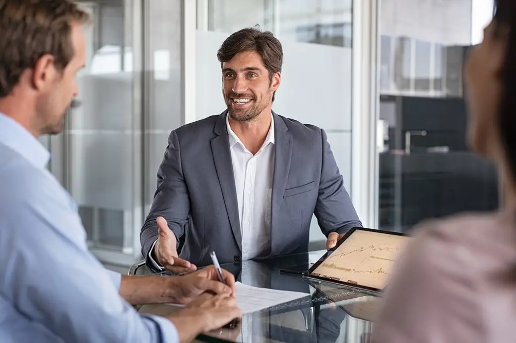 confident man in a gray suit leads an engaging discussion in a modern office meeting.