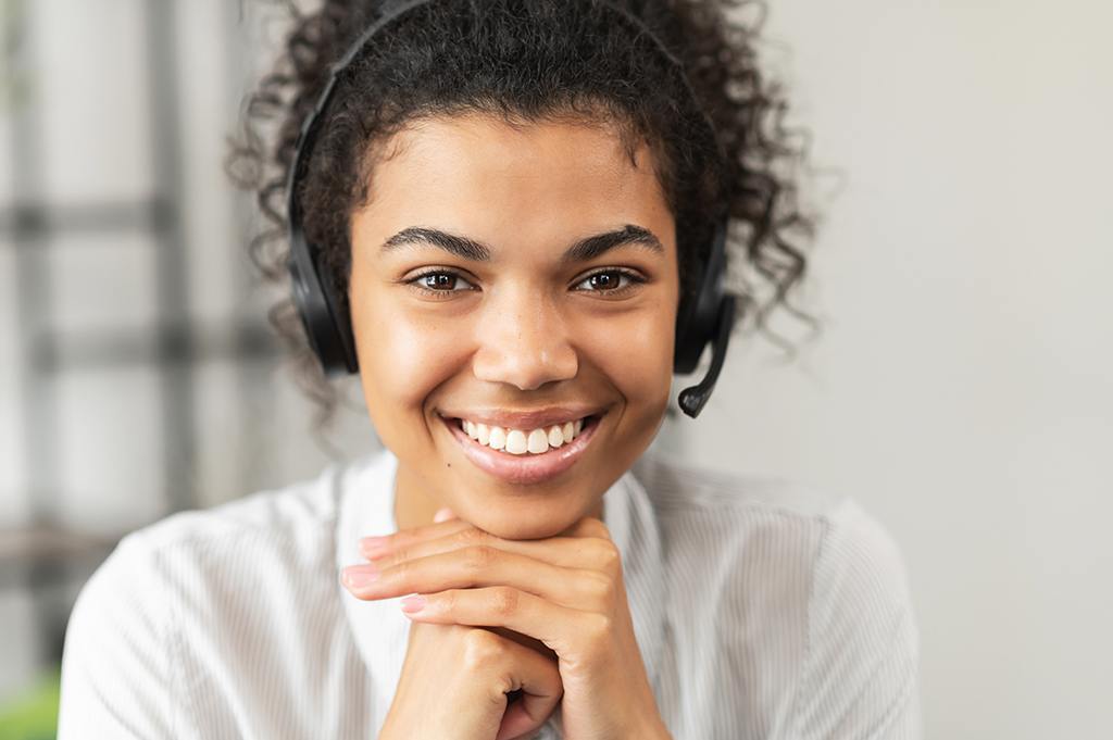 engaging it support representative smiling warmly in a modern workspace with headset.