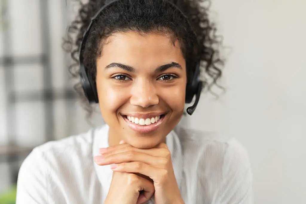 engaging it support representative smiling warmly in a modern workspace with headset.
