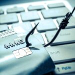 credit card phishing - piles of credit cards with a fish hook on computer keyboard
