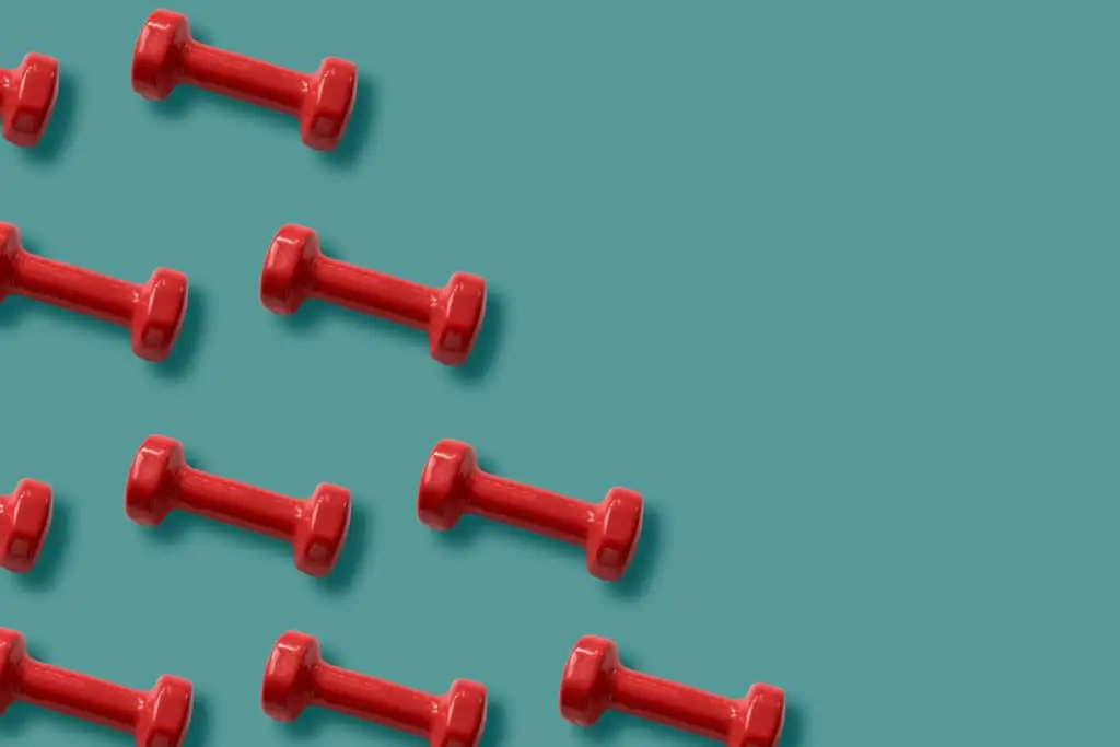 Strengths-Based Development Can Take Your Business To New Heights 2 vibrant red dumbbells scattered on a soothing teal background, symbolizing fitness and energy.
