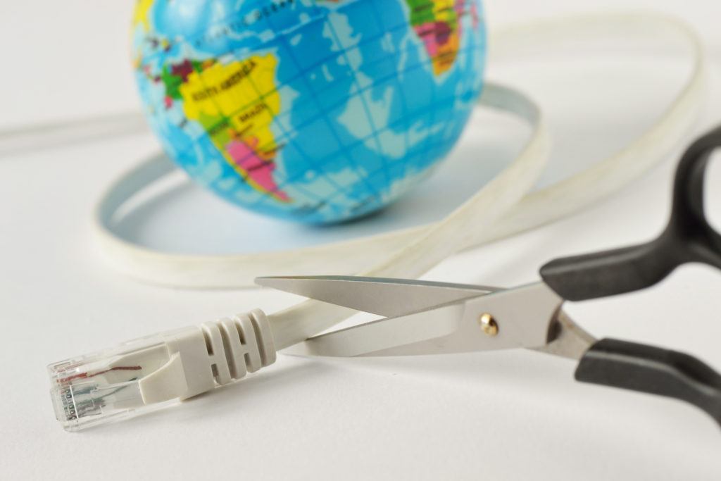 scissors poised to cut an ethernet cable beside a vibrant globe, symbolizing fragile global connectivity.