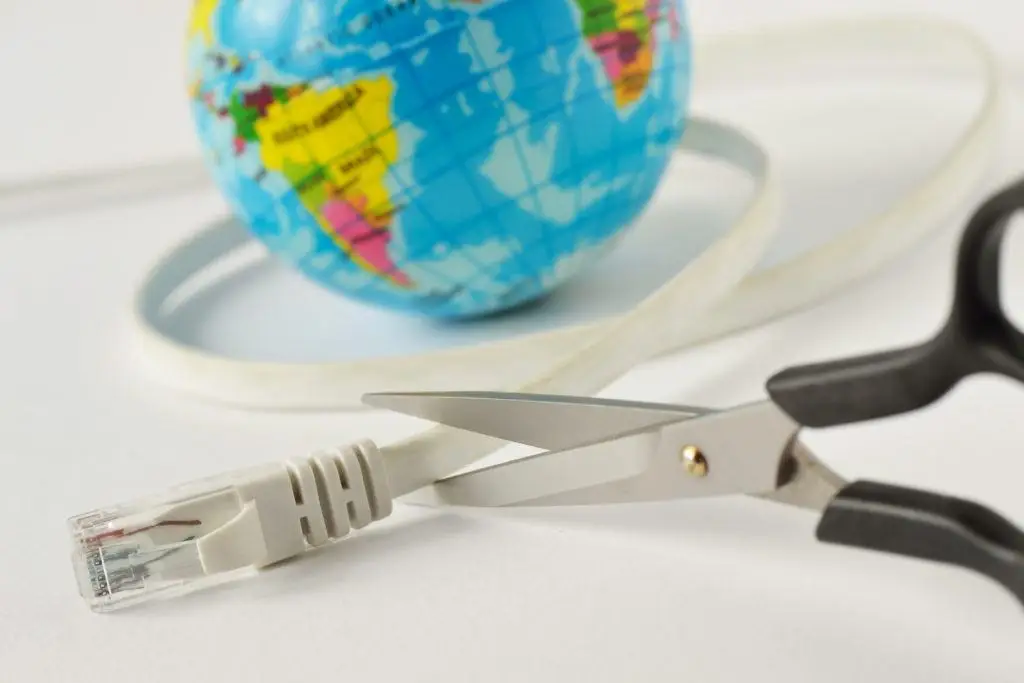 What A Global Internet Outage Tells About The Cloud And Your Business 2 scissors poised to cut an ethernet cable beside a vibrant globe, symbolizing fragile global connectivity.
