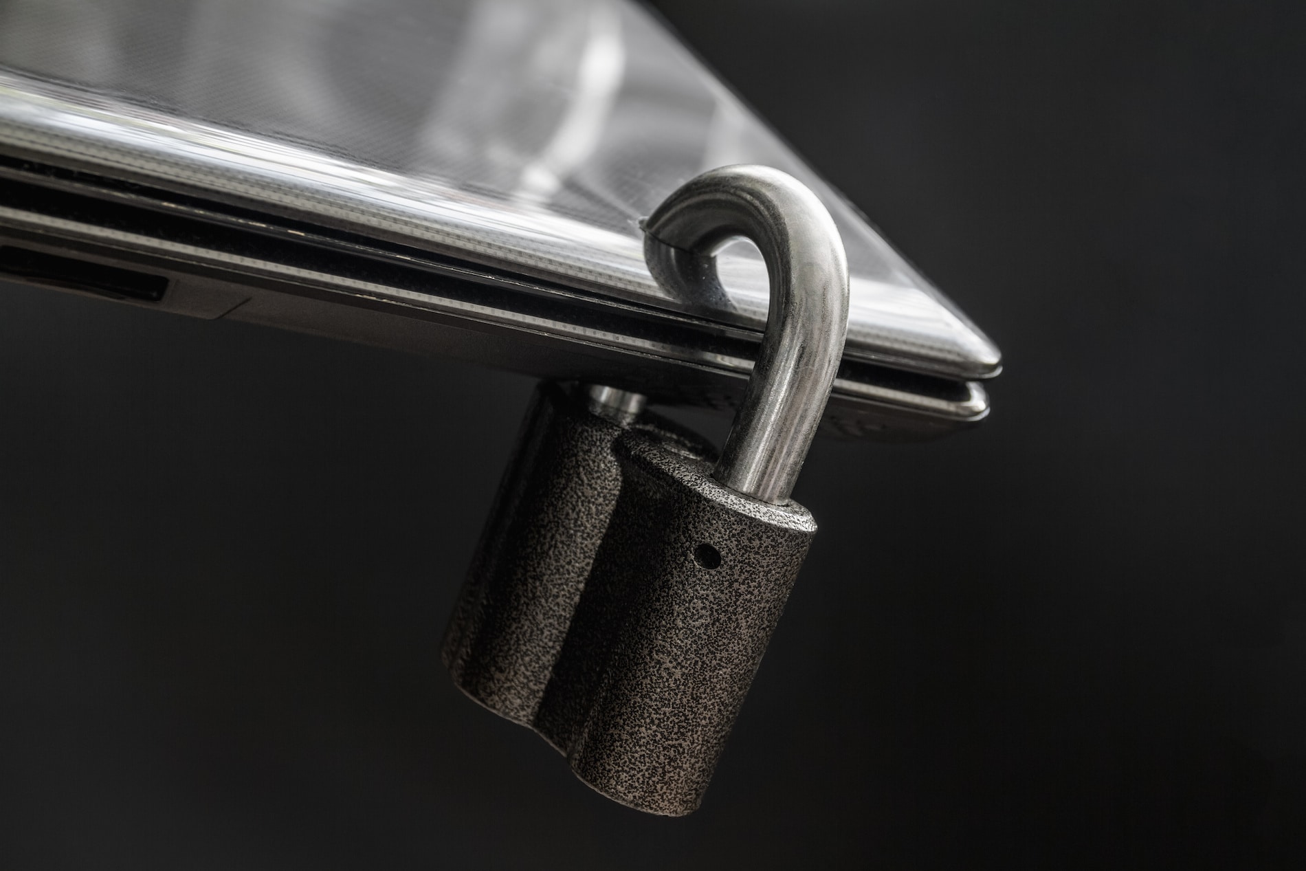 adobeLocked steel padlock in a drilled hole of the black laptop on dark background. Concept of protecting personal data on a computer. A laptop is locked with a lock. Closeup, selective focusstock. locking your phone and computer