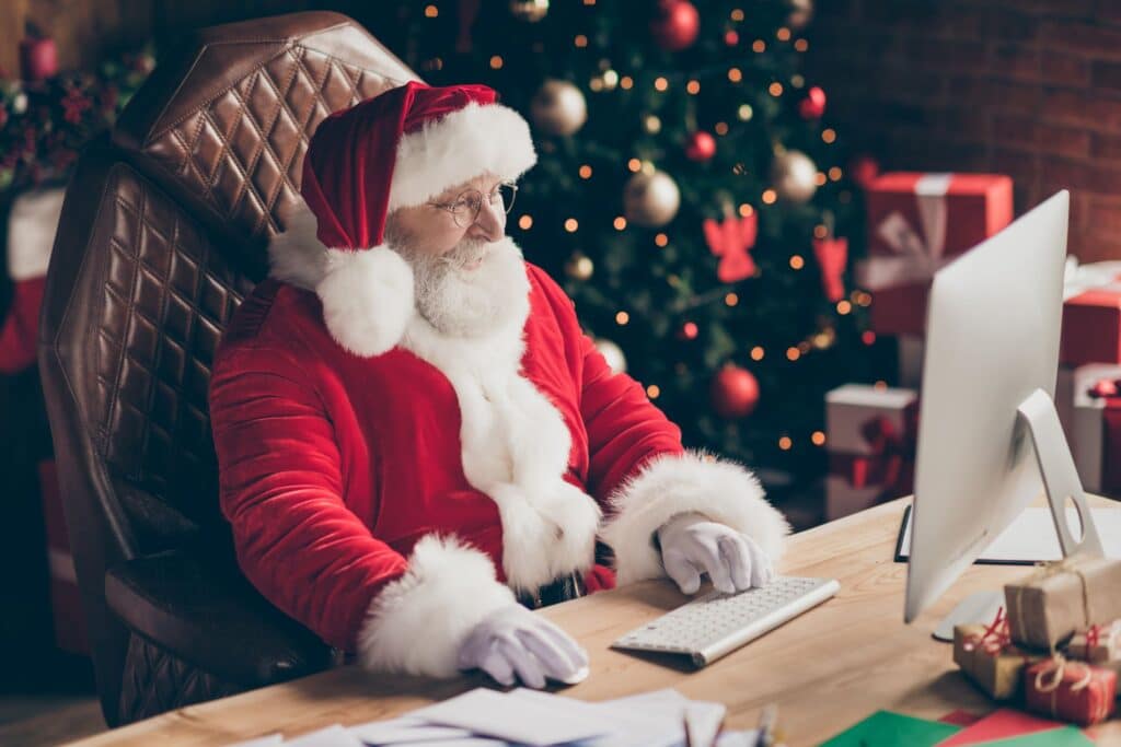 santa claus works at his desk in a festive north pole workshop, surrounded by gifts.