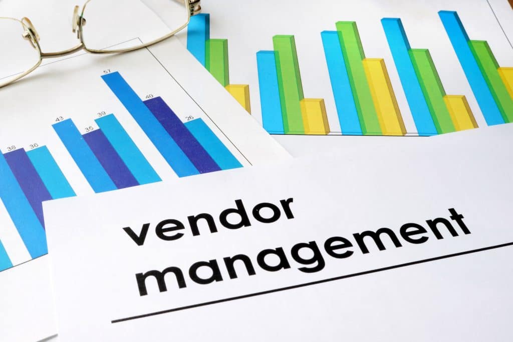 close-up of vendor management documents with graphs and glasses, highlighting performance analysis.