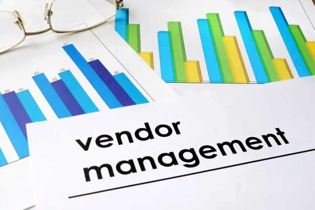 close-up of vendor management documents with graphs and glasses, highlighting performance analysis.